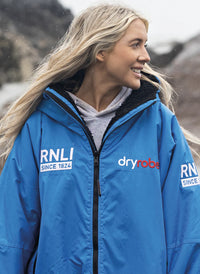 Person wearing a blue RNLI Dryrobe® change robe with visible branding
