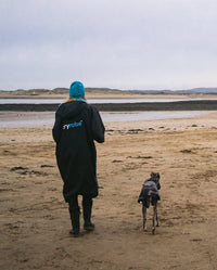 1|Woman walking away from camera on a beach with her dog, wearing Black Blue dryrobe® Advance Short Sleeve