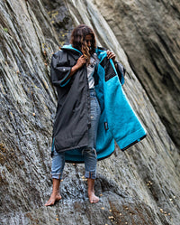 1|Woman stood on top of rocks on a beach, wearing Black Blue dryrobe® Advance Short Sleeve