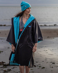 1|Woman stood in front of the sea in swimming costume, wearing Black Blue dryrobe® Advance Short Sleeve