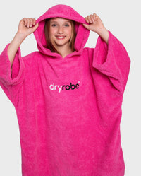 Girl pulling hood up on Kids Towel Poncho in Pink