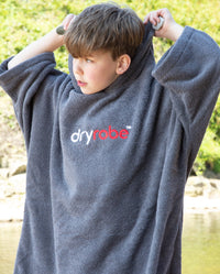 Boy wearing Kids Towel Poncho in Slate Grey, pulling up hood