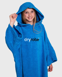 Girl wearing Cobalt Blue Kids Organic Towel poncho with hood up