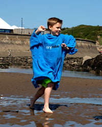 Boy running on beach wearing Cobalt Blue Kids Organic Towel poncho