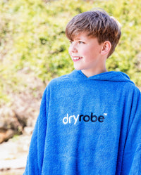 Boy smiling wearing Cobalt Blue Kids Organic Towel poncho
