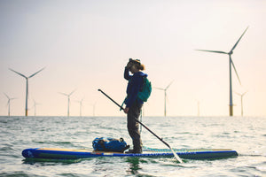 Cal Major stand up paddleboarding in front of an offshore wind farm