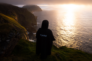 A woman stood on a cliff in a dryrobe looking down 