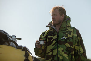 Andrew Cotton wearing a Camo dryrobe Advance and drinking coffee on the beach