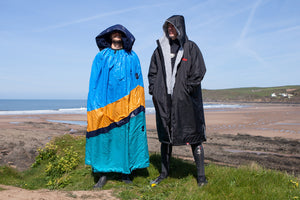 Two men standing by the beach wearing dryrobe changing robes