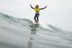 Girl surfing on longboard wearing USA Surfing competition jersey 