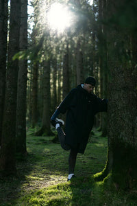 Person stretching in a forest with sunlight filtering through the trees