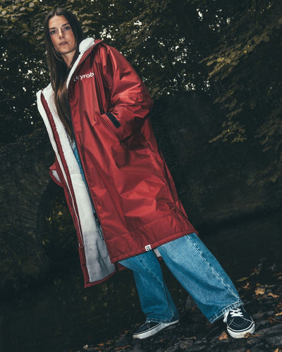 Female standing by stream and bridge  wearing AW25 Burgundy Dryrobe® advance long sleeve 