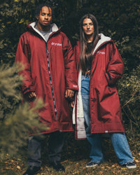 *MALE* and Female standing by hedge wearing AW25 Burgundy Dryrobe® advance long sleeve 