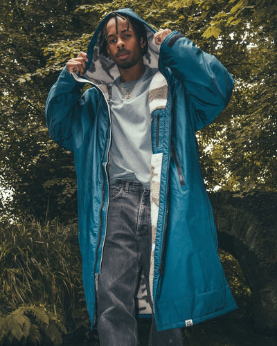 *MALE* standing next to bridge wearing AW25 Blue Dryrobe® advance long sleeve 