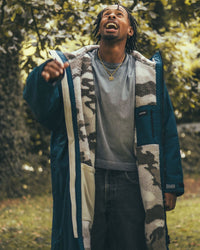 *MALE* standing under tree wearing AW25 Blue Dryrobe® advance long sleeve 