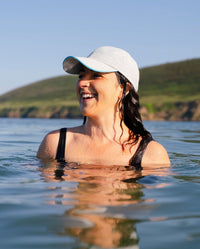 Woman swimming in water wearing grey Dryrobe® water resistant cap 