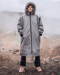 Man stood on misty hill, wearing dryrobe Advance Long Sleeve Alpine Range change robe in Alpine Graphite with hood up