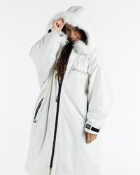 Woman wearing dryrobe Advance Long Sleeve Alpine Range change robe in Alpine White, pulling up hood
