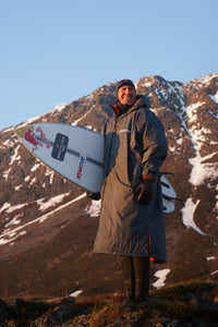 Person holding a snowboard with mountains in the background