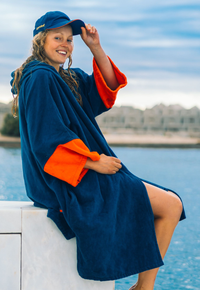 Female wearing deep sea blue dryrobe zip towel robe by outdoor pool