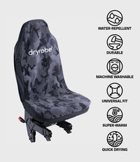 A Dryrobe car seat cover with a dark gray and black camouflage pattern, shown on a vehicle seat. The image features a vertical list of product benefits on the right side, including 'Water-Repellent', 'Durable', 'Machine Washable', 'Universal Fit', 'Super-Warm', and 'Quick Drying', all with simple black icons on a light gray background.