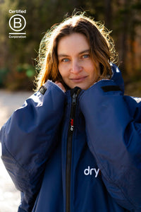 Person wearing a blue jacket with 'dryrobe' branding, standing outdoors.
