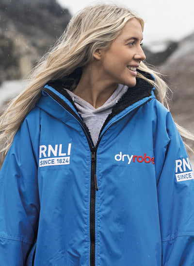 Person wearing a blue RNLI Dryrobe® change robe with visible branding
