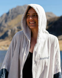Adult female by water wearing Dryrobe® Zip towel (nimbus cloud)