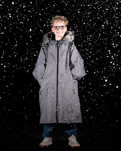 Boy stood in snow wearing dryrobe Advance Long Sleeve Changing Robe Alpine Range in Alpine Graphite 
