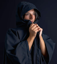 Person wearing a dark hooded cloak against a black background