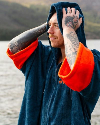 *MALE* by water wearing Dryrobe® Zip towel (blue orange)