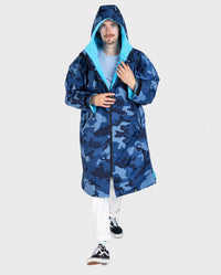 **MALE** Man walking toward 
camera wearing dryrobe Advance Long Sleeve changing poncho in Blue Camo Blue with hood up 