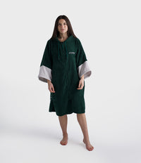 Person wearing a green poncho with white cuffs and hem on a white background