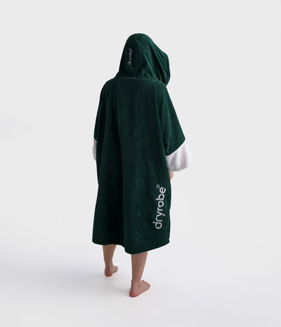 Person wearing a green hooded towel with 'dryrobe' branding on a white background