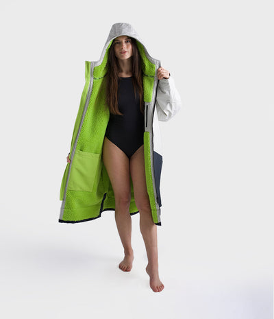 Person wearing a bright green hooded Dryrobe on a white background