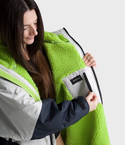 Woman wearing a green and white Dryrobe with a visible brand logo on a light grey background