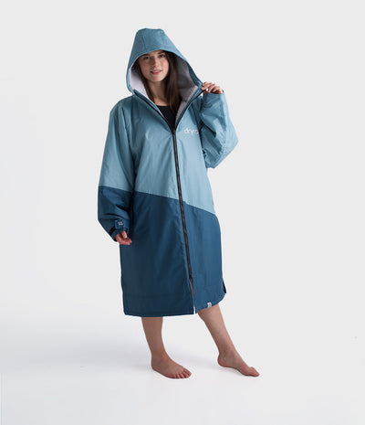 Person wearing a blue and grey hooded Dryrobe on a white background
