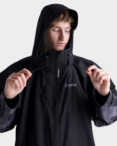 *MALE*Person wearing a black jacket with a hood, featuring the brand 'Dryrobe'.