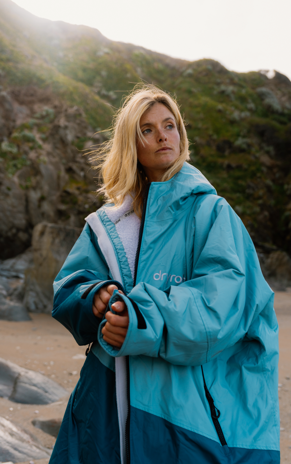 Person wearing a blue dryrobe on a rocky beach