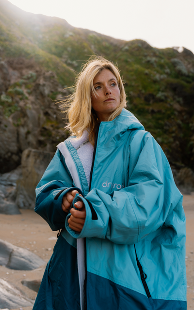 Person wearing a blue dryrobe on a rocky beach