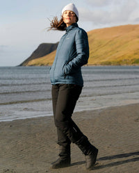 Woman walking along beach, wearing dryrobe® Thermal Trousers and dryrobe® Mid-Layer Jacket in Deep Sea Blue 