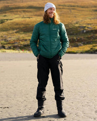 *MALE* Man stood on a beach, wearing dryrobe® Thermal Trousers and dryrobe® Mid-Layer Jacket in Hunter Green