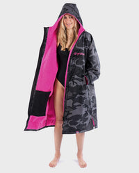 Woman smiling wearing dryrobe Advance Long Sleeve REMIX Range change poncho in Black Camo Pink Black with hood up 