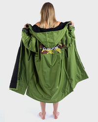 Woman standing with back to the camera, wearing  dryrobe Advance Long Sleeve REMIX Range change poncho in Forest Green Black Camo