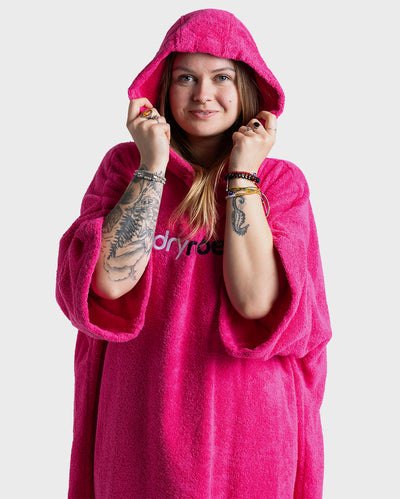 Woman wearing dryrobe® Organic Cotton Towel Poncho in Pink with the hood up 