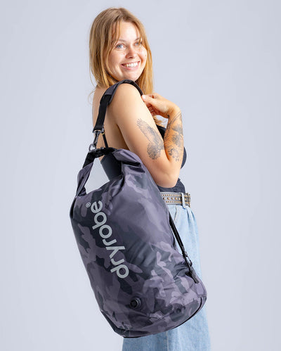 Woman in studio carrying black camo Dryrobe® compression bag 