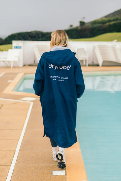 Person wearing a blue customised Dryrobe® changing robe by a poolside