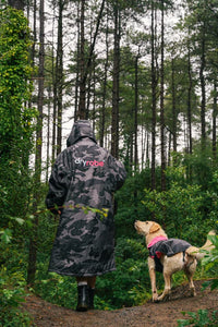 Person and dog wearing Dryrobe® change robes in a forest setting
