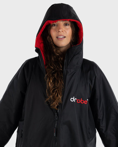 Woman wearing dryrobe Advance Long Sleeve changing robe in Black Red with hood up