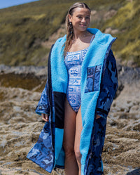 Woman on a beach wearing dryrobe Advance Long Sleeve changing poncho in Blue Camo Blue, unzipped